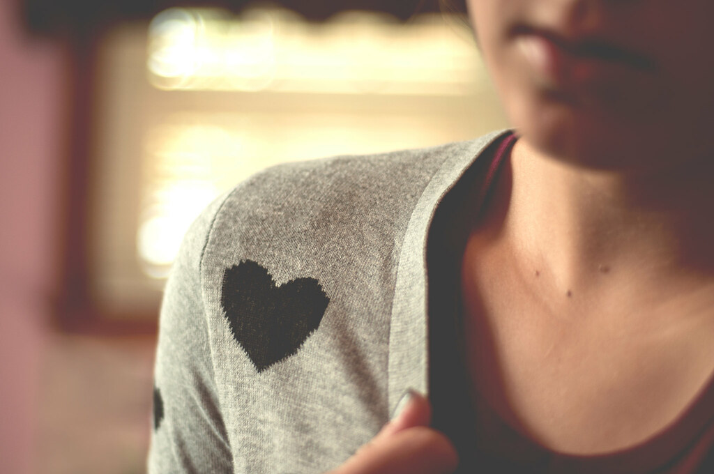 photo of a young person wearing a gray cardigan with a black heart on the shoulder